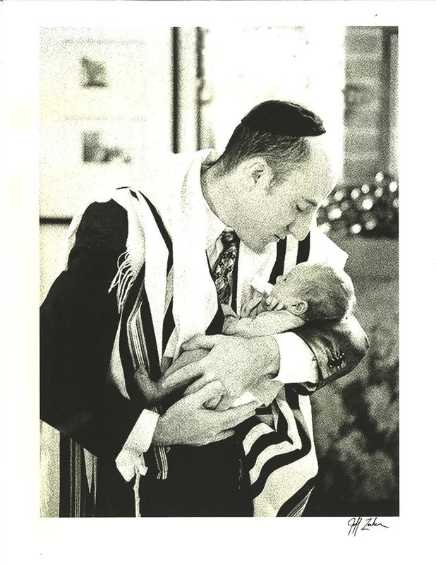 A signed print of Rabbi Denbo cradling a newborn